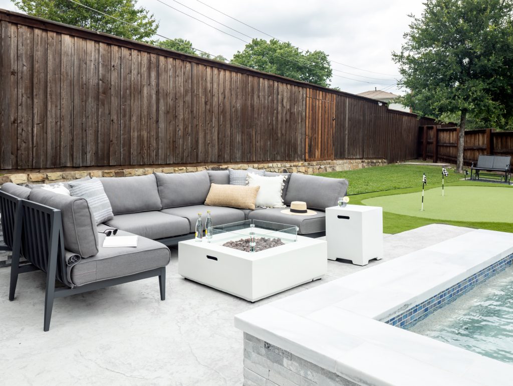 backyard exterior design with gray patio furniture, pool, and putting green